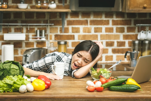 Fatigué jeune belle fille dormant sur la table de la cuisine. Stress.