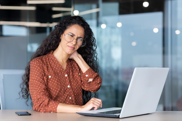 Fatigué jeune femme d'affaires latino-américaine pigiste, il est assis au bureau dans le bureau fait des heures supplémentaires