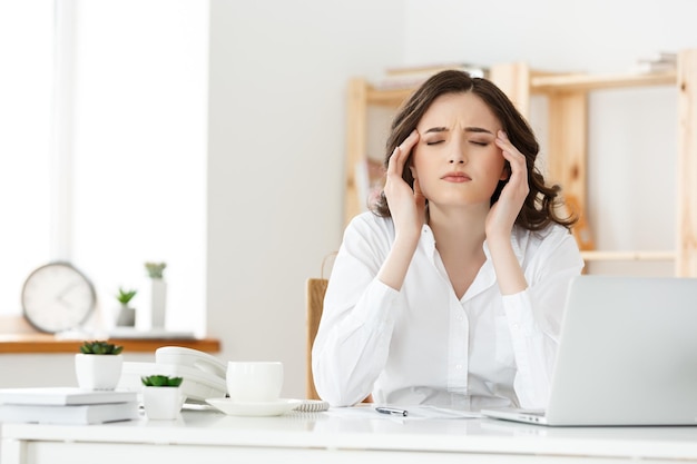 Fatigué de jeune femme d'affaires souffrant de longue période assis au bureau d'ordinateur dans le bureau