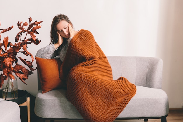 Fatigué de jeune femme allongée sur le canapé sur fond de mur blanc. Mal de tête.