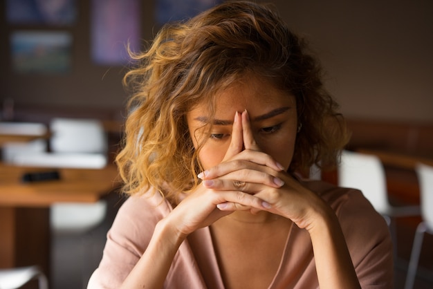 Photo fatigué de jeune femme penchant la tête sur les mains