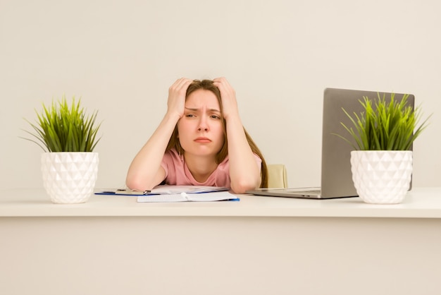 Fatigué de jeune femme stagiaire surmené travaillant avec un ordinateur portable dans un bureau