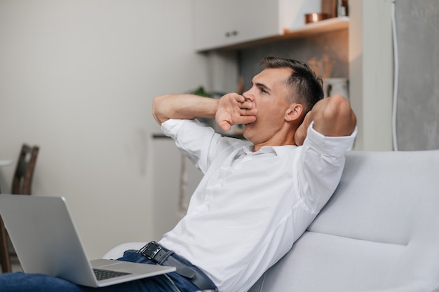 fatigué jeune homme regardant son écran d'ordinateur portable.