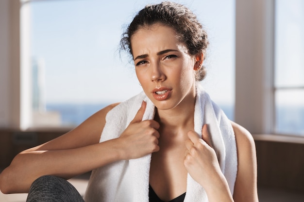 Fatigué de jeune sportive assise avec une serviette sur ses épaules