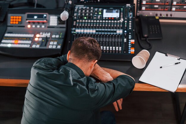 Fatigué par le travail Le jeune homme est à l'intérieur dans le studio de radio est occupé par la diffusion
