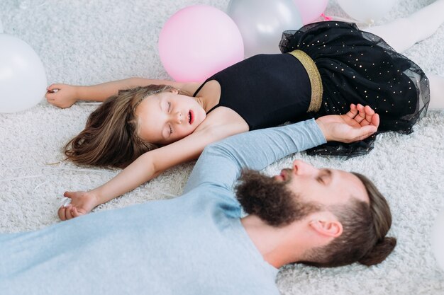 fatigué, le père épuisé a assommé et s'est endormi avec une petite fille hyperactive. paternité et enfance doux moments.