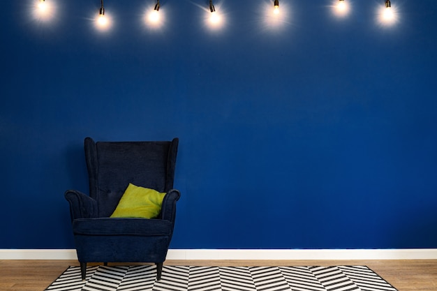 Fauteuil bleu foncé contre le mur bleu dans le salon moderne