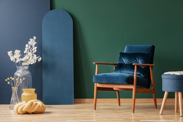 Fauteuil bleu foncé rétro dans un intérieur élégant de salon avec espace de copie sur un mur vert et bleu vide