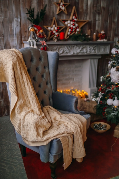 Fauteuil confortable avec couverture se tient devant un arbre de Noël