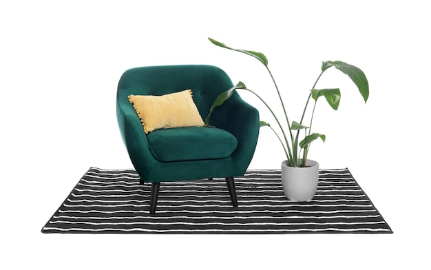 Fauteuil confortable élégant avec une plante d'intérieur sur oreiller et un tapis rayé isolé sur blanc