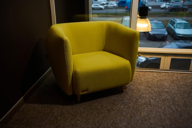 Fauteuil jaune moderne et confortable dans le couloir du magasin de meubles sur fond de grandes fenêtres affiché à la vente Design d'intérieur de bureau et de maison