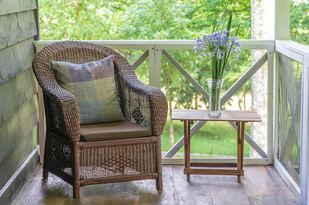 Fauteuil en rotin et table avec un vase de fleurs sur une véranda en bois Afrique Tanzanie close up