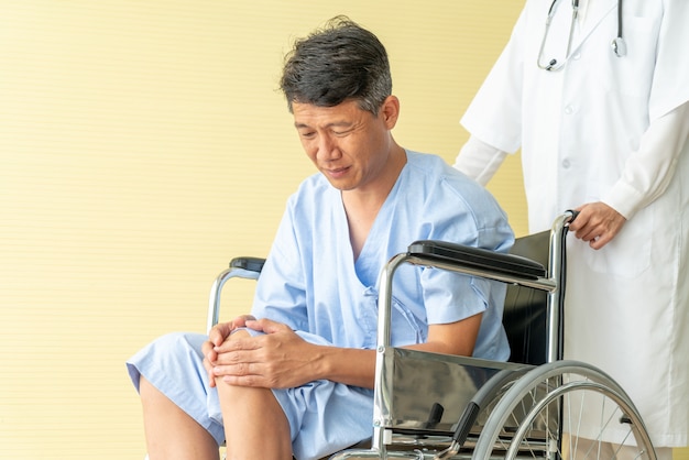 Fauteuil roulant patient senior asiatique avec douleur au genou