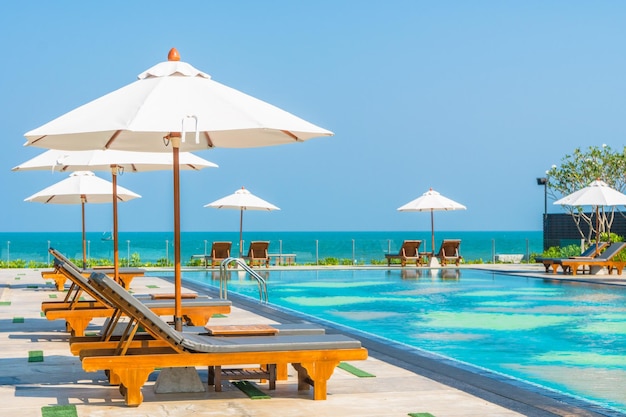 Des fauteuils longs avec parapluie près de la piscine contre un ciel dégagé