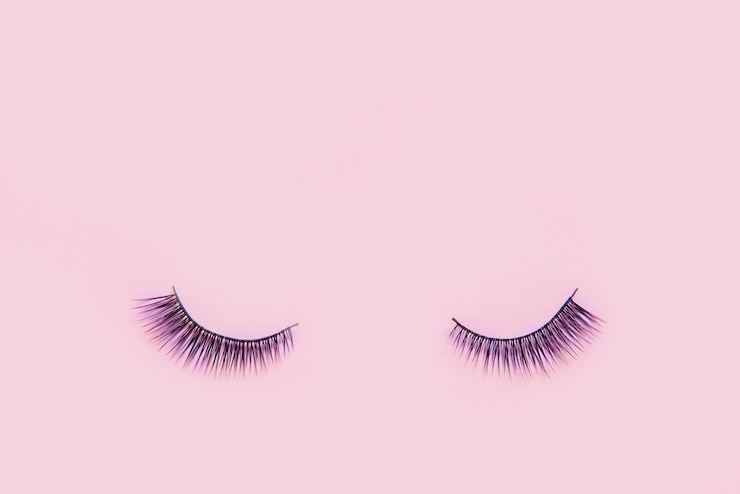 Photo faux cils sur la couleur rose avec espace copie