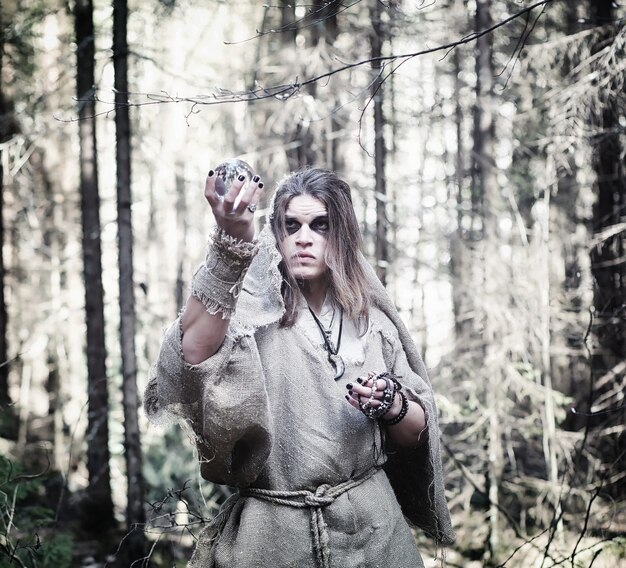 Fée magicienne. Un sorcier avec une sphère de verre, un sortilège et un rituel. Aîné avec un bâton et une croix dans la forêt. Magie noire et blanche. Un sort dans un vieux livre.