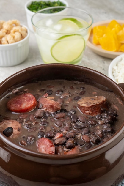 Feijoada brésilienne traditionnelle avec craquelins d'orange de chou frisé de riz et caipirinha