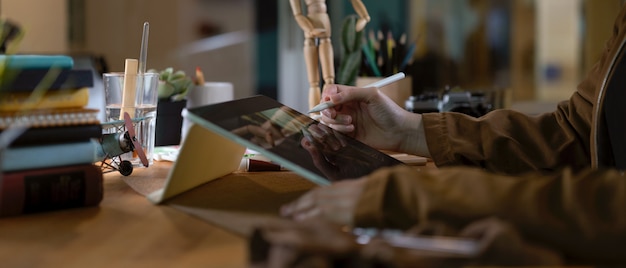 Female college student faisant la cession avec tablette numérique, livres et papeterie sur table en bois