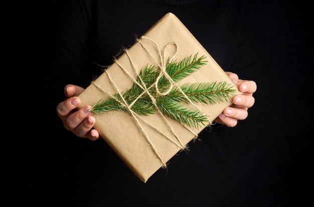 Female hands holding boîte-cadeau de Noël sur fond noir