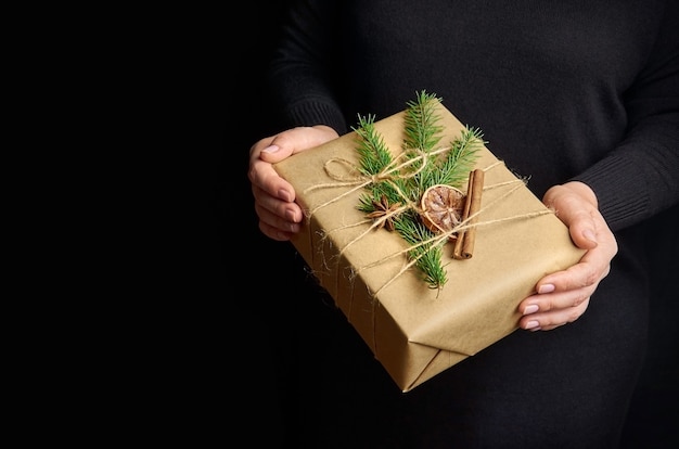 Female hands holding boîte-cadeau de Noël sur fond noir