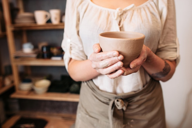 Female hands holding bol de poterie en atelier