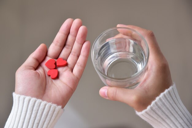 La femelle tient des pilules rouges en forme de coeur.