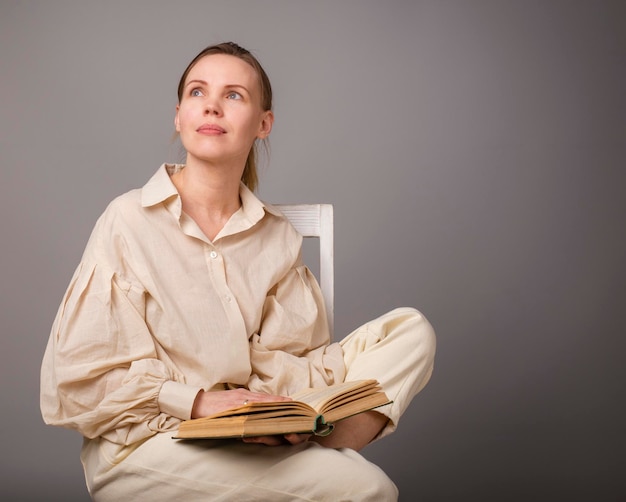 Femme de 40 ans avec un livre sur fond clair