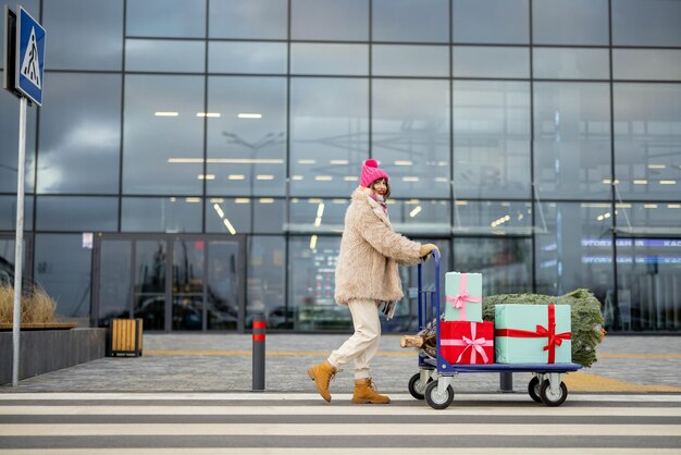 Une femme achète un arbre de noël et des cadeaux au centre commercial