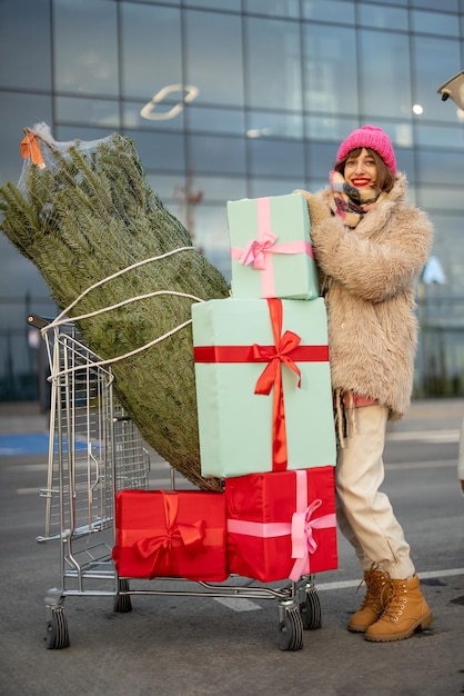 Une femme achète un arbre de noël et des cadeaux au centre commercial