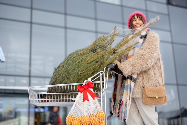 Une femme achète un arbre de noël et des fruits au centre commercial