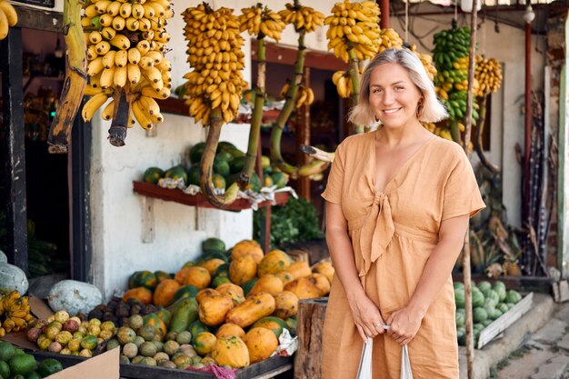 Femme acheter des fruits frais au marché local exotique