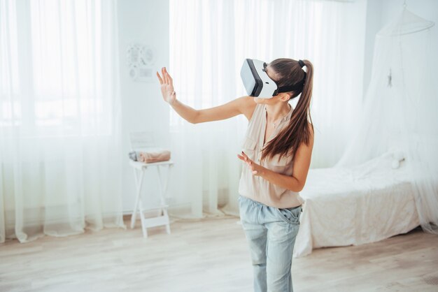 Une femme acquiert de l'expérience en utilisant un casque de réalité virtuelle avec des lunettes VR dans un environnement lumineux