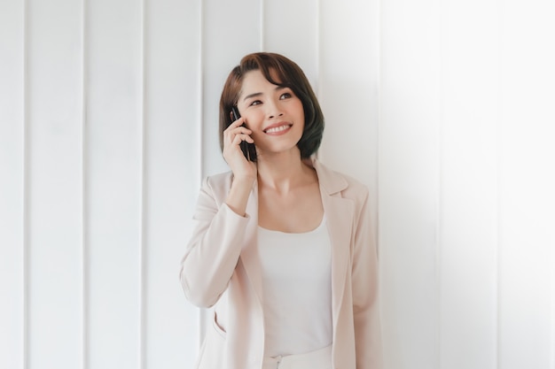 Une femme active asiatique heureuse a une conversation avec un smartphone