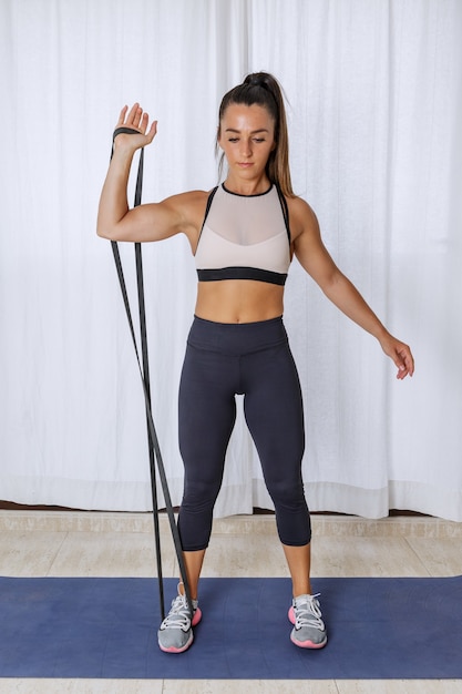 Femme active faisant des exercices de biceps avec bande de résistance