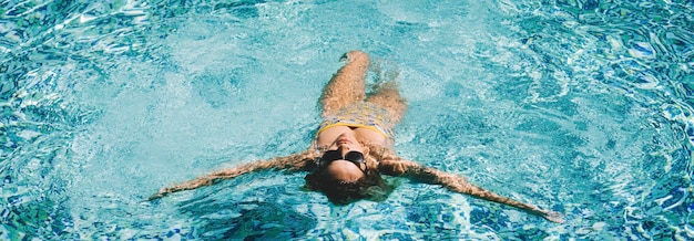 Femme active nageant dans l'eau bleue de la piscine et profitant des vacances d'été Gens dans les activités de loisirs en plein air Dame en journée de détente nager et profiter de la détente En-tête de bannière Mode de vie sain