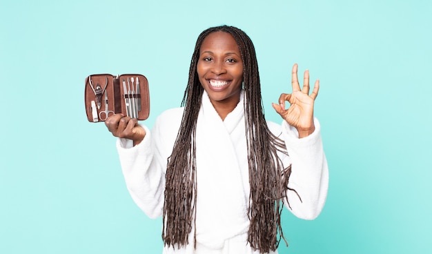 Femme adulte afro-américaine noire portant un peignoir et tenant un sac de maquillage avec des outils nains