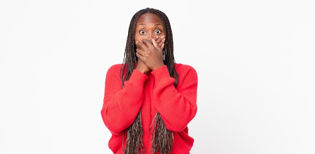 Femme adulte afro noire couvrant la bouche avec les mains avec une expression choquée et surprise, gardant un secret ou disant oops