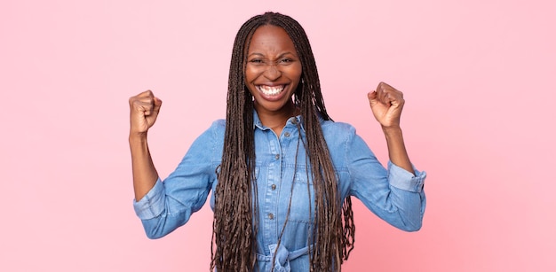 Femme adulte afro noire se sentant heureuse, positive et réussie, célébrant la victoire, les réalisations ou la bonne chance