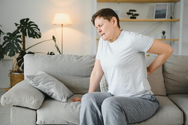 Femme adulte âgée touchant le dos se sentant mal au dos inconfort douleur musculaire lombaire basse au rein