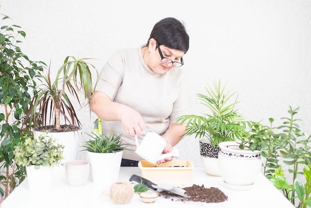 Une femme adulte arrosant des graines de fleurs avec un arrosoir dans un pot