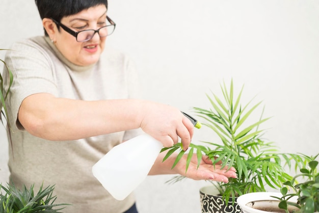 Une femme adulte arrose une fleur dans un pot