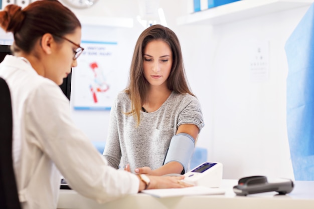 Femme adulte ayant un test de pression artérielle lors d'une visite au cabinet d'un médecin féminin