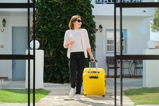 Femme adulte avec des bagages avec valise se rendant dans le hall de l'hôtel