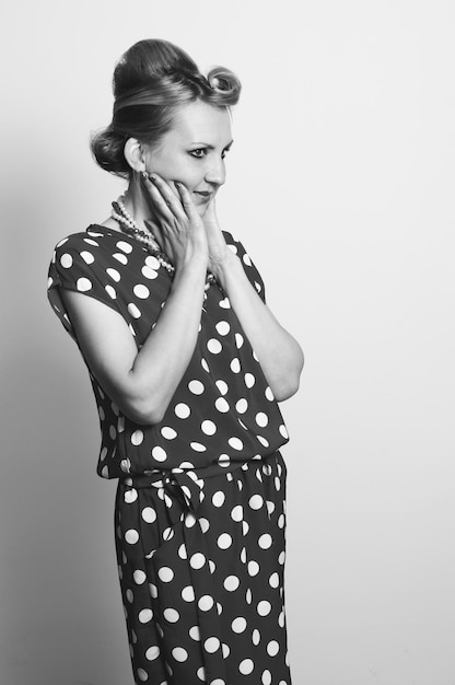 Photo une femme adulte choquée dans des vêtements de style rétro se tient la tête dans les mains sur un fond gris