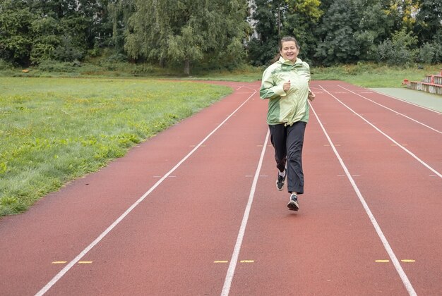 Une femme adulte court à l'extérieur dans le stade