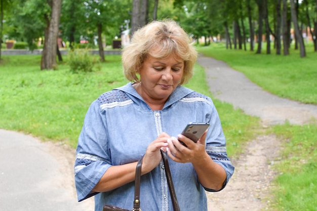 femme adulte dans un parc parlant au téléphone femme âgée communique en ligne