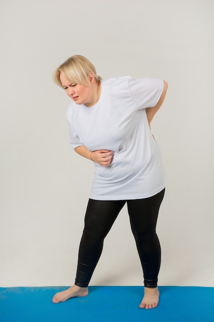 Femme adulte dans un t-shirt blanc ayant mal au dos