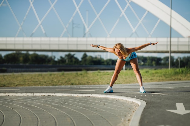 Femme adulte faisant des exercices d'étirement tout en s'échauffant pour l'entraînement sportif près de la rivière.