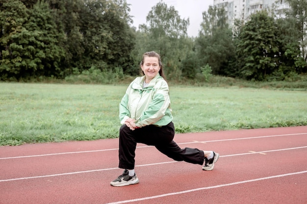 Une femme adulte fait des exercices physiques dans un stade extérieur