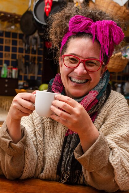 Femme adulte avec un foulard souriant et buvant du café